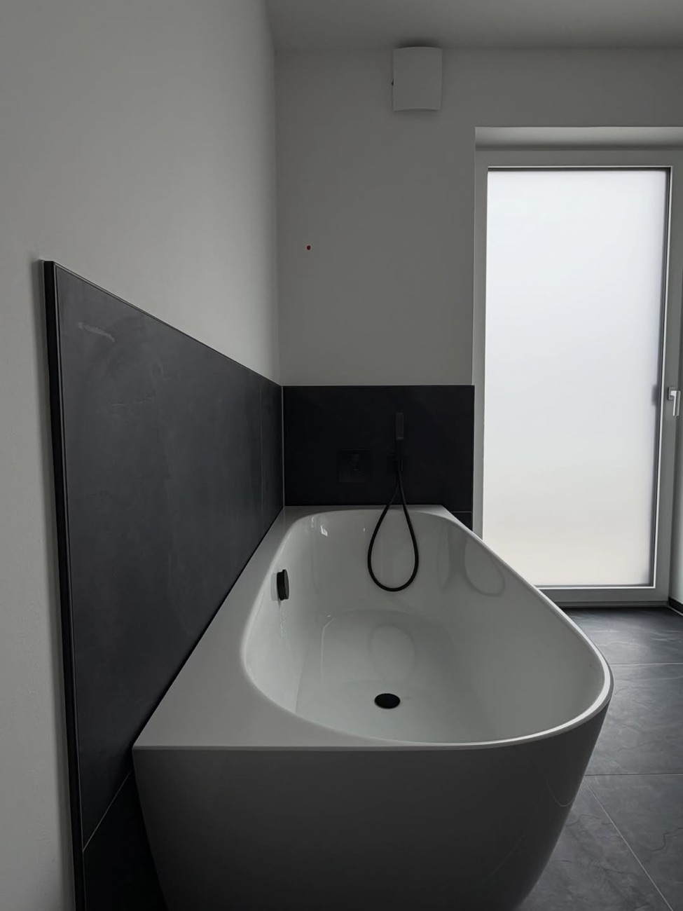 Freistehende Badewanne vor anthrazitfarbener Wand