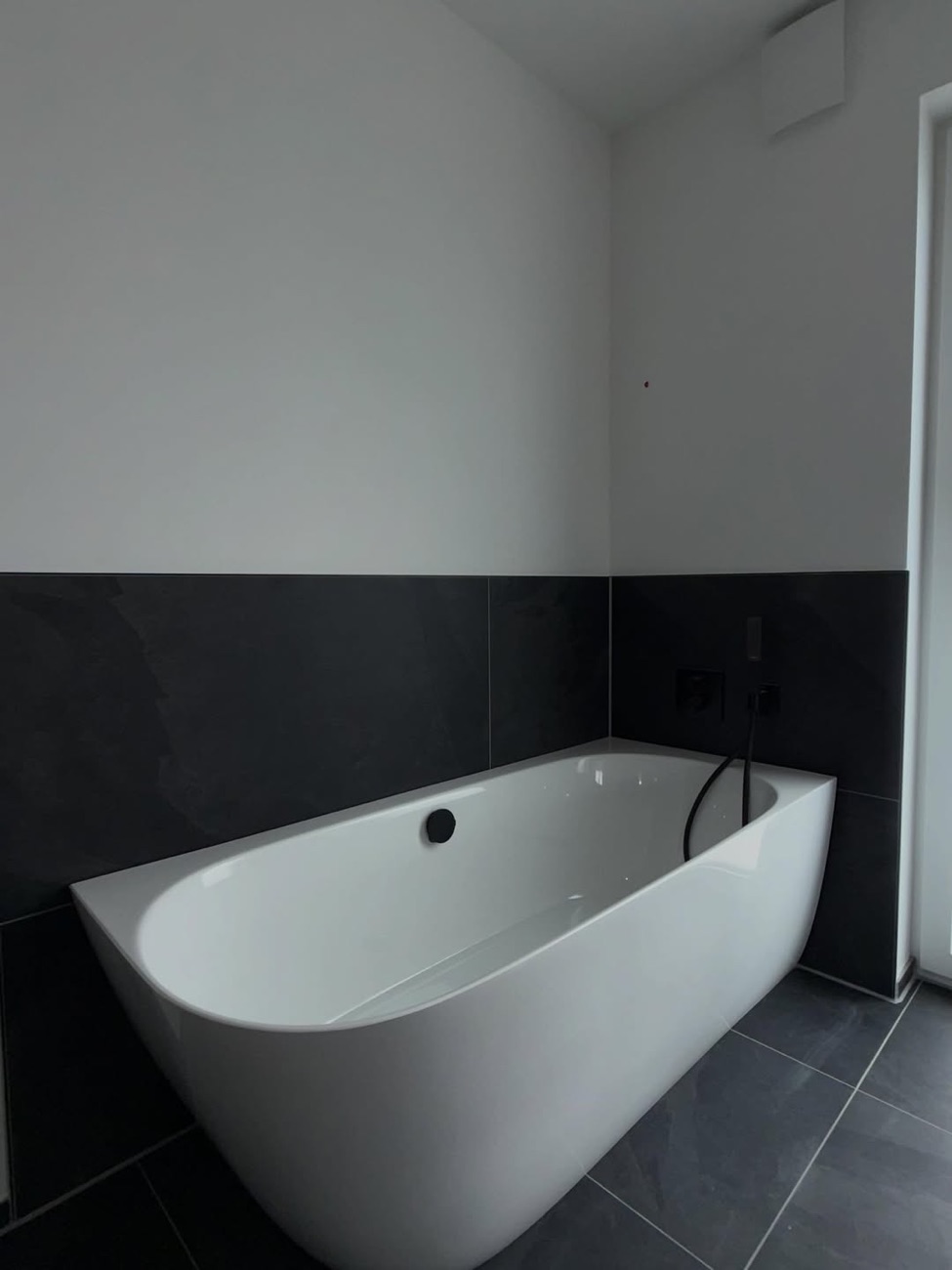 Freistehende Badewanne mit schwarzen Armaturen