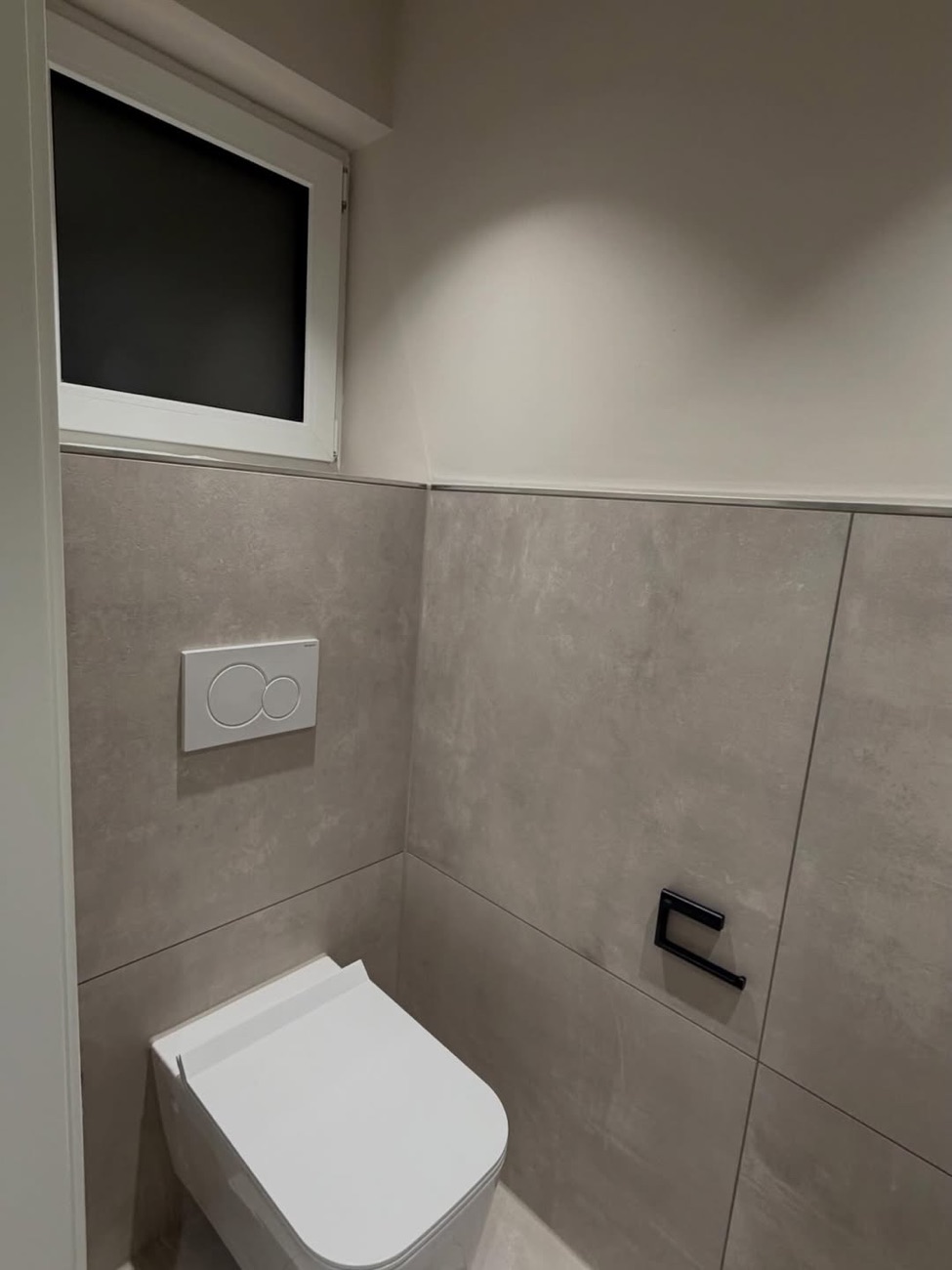 Gäste-WC mit Wand-WC und grauen Fliesen