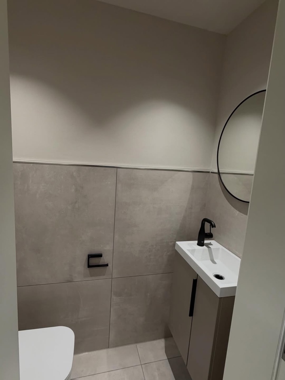 Gäste-WC mit rundem Spiegel und schwarzer Armatur