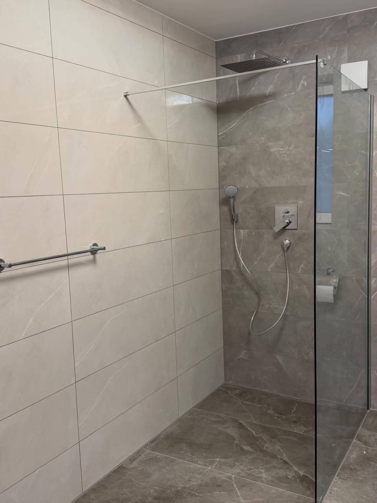 Bad in Naturstein-Optik mit bodengleicher Dusche und Glaswand