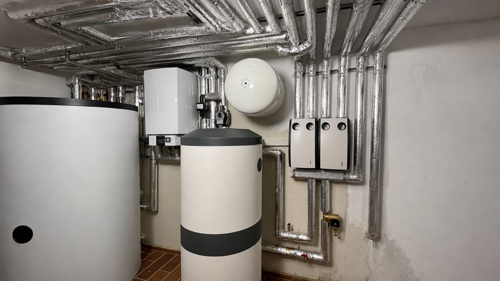 Von Atasoy installierte Wärmepumpen-Anlage mit Puffer- und Warmwasserspeicher, Wohnraumlüftung und sauber gedämmter Verrohrung im Technikraum